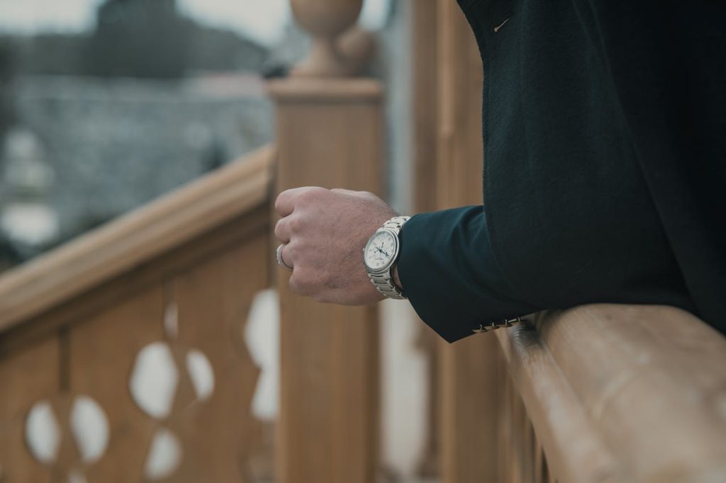 A man wearing a suit and a watch on a wooden railing